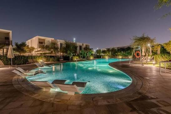 Resort-style pool at Tilal Al Ghaf at night with contemporary villas and landscaped gardens